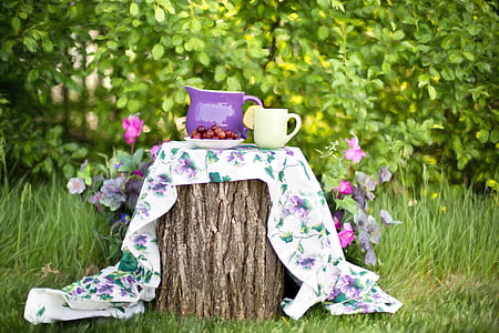 two purple and yellow ceramic cup and pitcher on multicolored floral textile