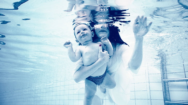 woman holding baby while underwater