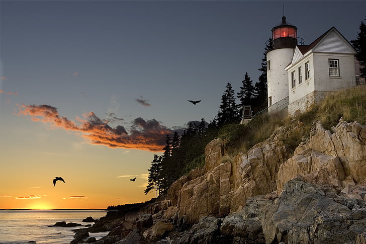 low angle view of lighthouse near body of water during golden hour