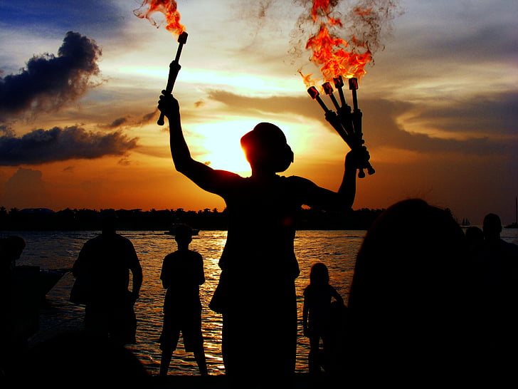 silhouette of person holding torch with flames