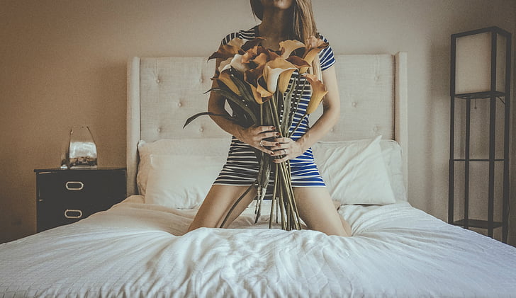 photo of woman holding flowers on top of bed