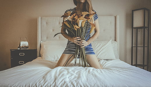 photo of woman holding flowers on top of bed