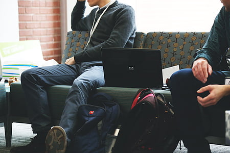 men wearing black sweater beside laptop during daytime