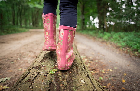 selective focus photography of person in pink floral boots walking on tree trunk