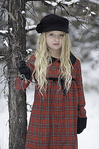 girl wearing red and white plaid coat holding tree branch