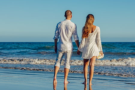 man and woman walking on seashore