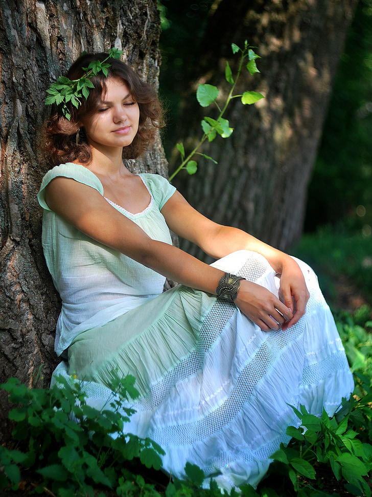woman in white and green cap-sleeved dress lying on tree