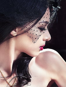 woman in red lipstick and black polka-dot mesh headdress