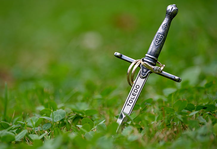silver-colored sword on green grass