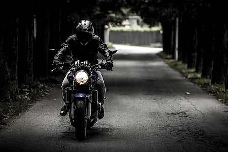 grayscale photo of man in jacket riding motorcycle