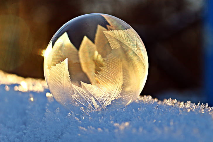shallow focus of clear glass ornament on snow