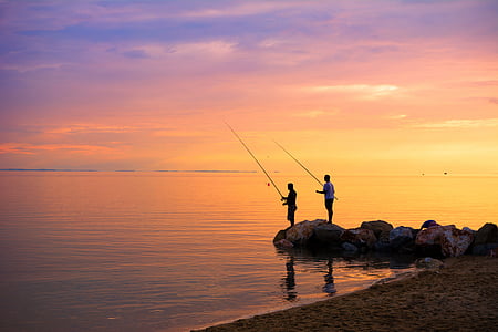 two men fishing standing on stones