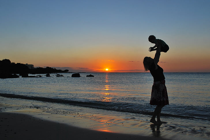 woman carrying baby near seashore
