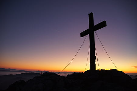 silhouette of cross on mountain peak during golden hour