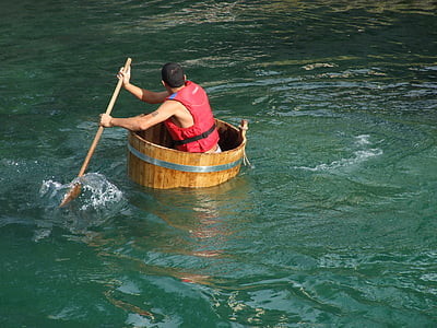 man on brown wooden boat holding a paddle