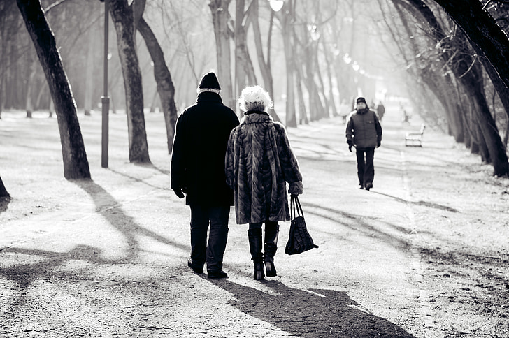 grayscale photo of people walking on pathway between trees