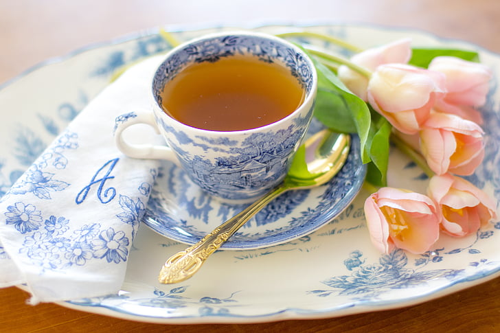 teacup on saucer beside pink flowers