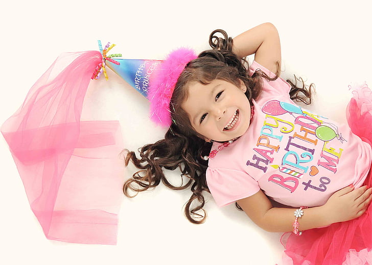 girl wearing pink Happy Birthday-printed top lying photo