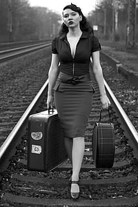 greyscale portrait photograph of woman carrying two luggages