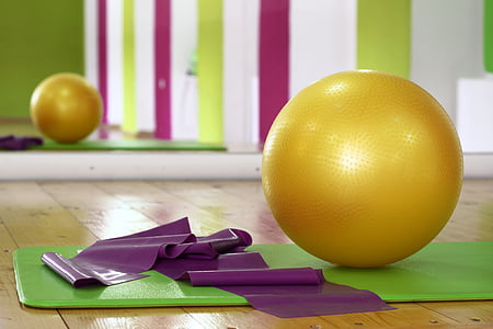 round yellow gym ball and green yoga mat