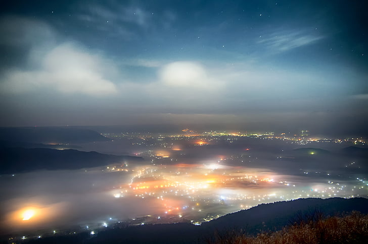 aerial photography of city light near fogs and mountain