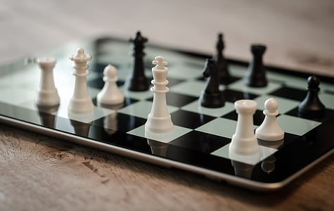 white and black chess pieces on black tablet computer