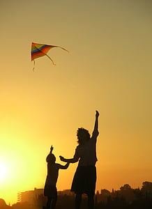 person flying an orange, green, and blue kite