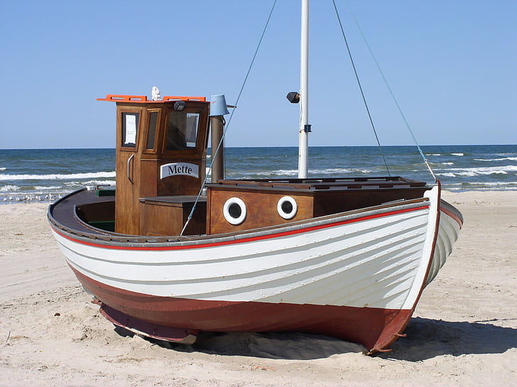 white and brown boat on gray sand