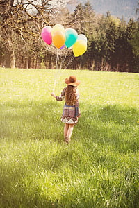 woman in brown and blue dress holding balloons