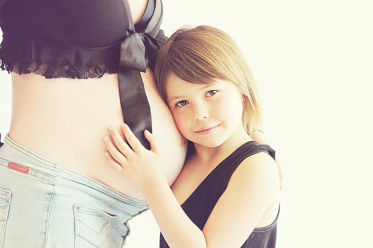 boy in black tank top leaning on woman's belly