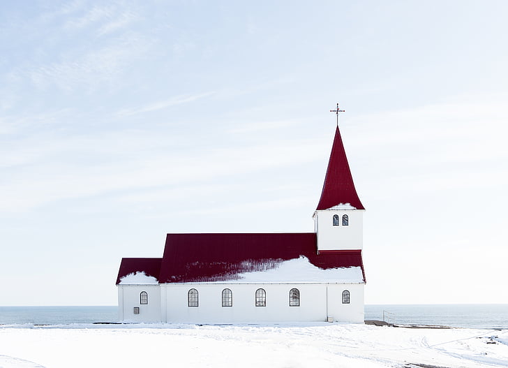 red and white chapel near body of water