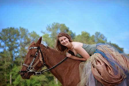 woman in green and brown dress riding horse