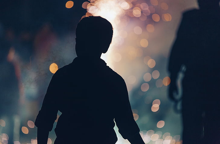 silhouette photo of boy with bokeh background
