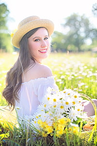 selective focus photography of woman sitting on grass surrounded by grass and white daisy flowers during daytime