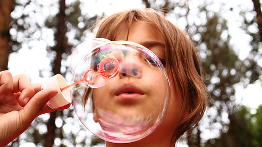 selective focus photography of girl blowing bubbles