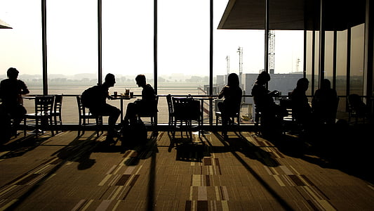 silhouette of people sitting on chair beside glass wall