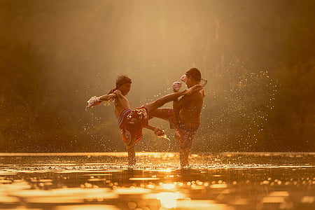 two boy playing in water during golden hour