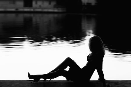 silhouette of woman over dock grayscale photo