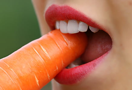 woman with red lipstick bites carrot